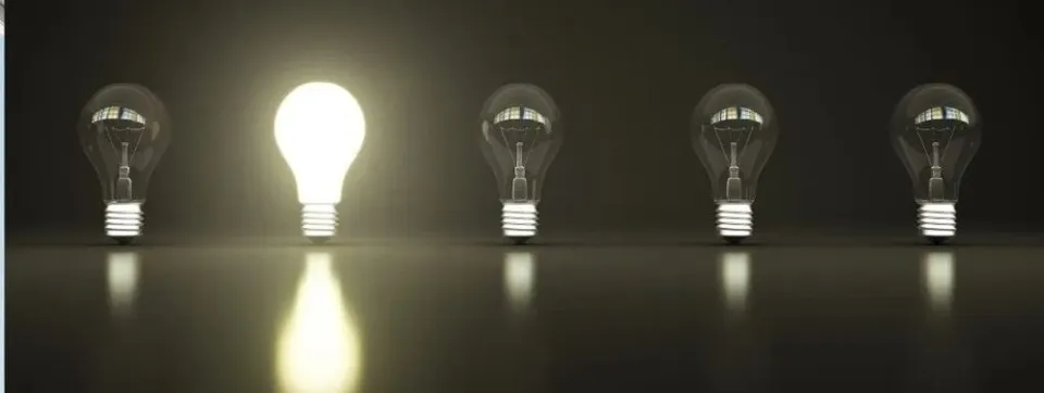 Cinci becuri sunt așezate într-un rând pe o suprafață întunecată, dintre acestea unul este aprins și emite o lumină puternică.