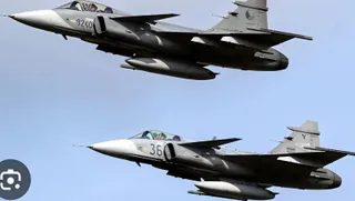 Două avioane de vânătoare gri zboară pe un cer senin.