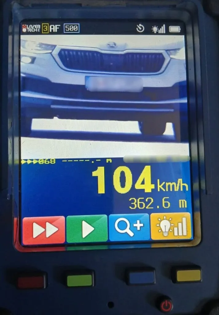 Ecranul unui dispozitiv electronic afișează numărul 104 km/h și o distanță de 362.6 m deasupra unor butoane colorate.