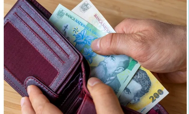 O persoană ține un portofel deschis de culoare purpurie din care scoate câteva bancnote de 200 de lei.