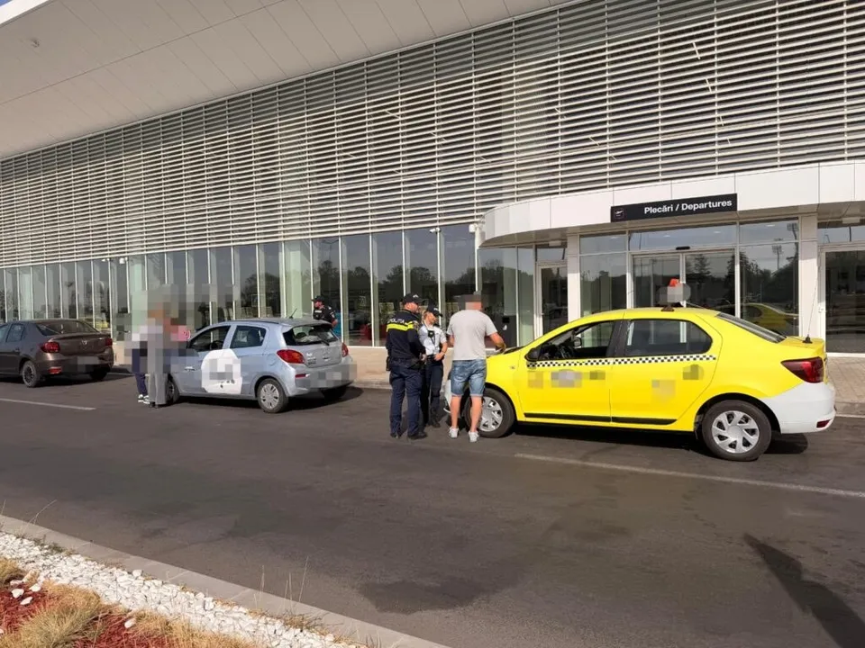 Un grup de persoane stă lângă un taxi galben și o mașină gri în fața unei clădiri cu suprafețe vitrate mari.