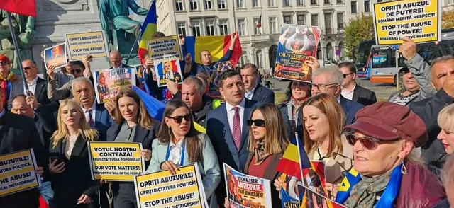 O mulțime de oameni strânge diverse afișe și steaguri colorate într-un spațiu public deschis, în fața unor clădiri urbane.