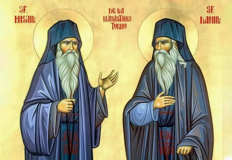Două figuri masculine cu barbă lungă și albă poartă haine monahale albastre și au aureole aurii în jurul capelor pe un fundal galben.