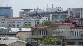 Vederea de la înălțime asupra unor acoperișuri de clădiri urbane cu elemente de utilități și diverse structuri de beton sub un cer deschis.