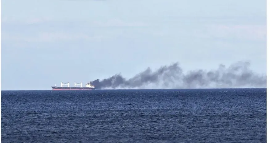 Un vapor mare de culoare închisă navighează pe o suprafață de apă, lăsând în urmă un nor lung de fum negru pe orizont.