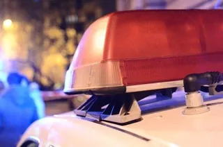 O lumină de avertizare roșie este montată pe acoperișul unui vehicul alb, în timp ce fundalul este neclar și luminat.