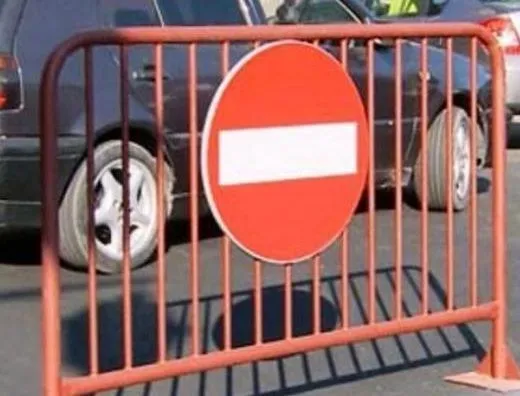 Un semn de intrare interzisă, circular și roșu cu o bară albă orizontală, este montat pe o barieră metalică de culoare roșie.