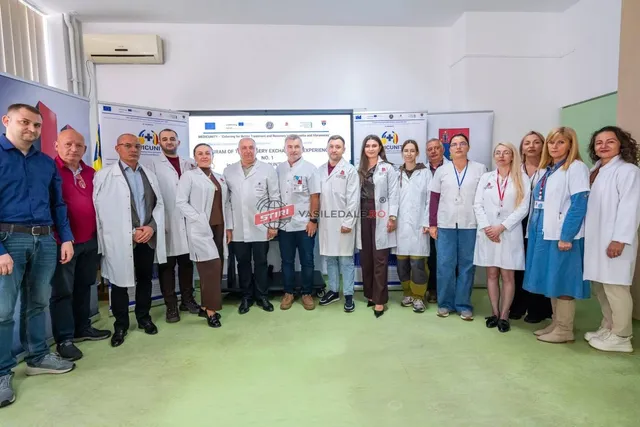 Un grup de persoane stă în rând într-o încăpere, majoritatea purtând halate albe de laborator.