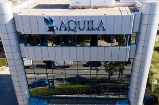 O clădire cu fațadă de sticlă și panouri gri prezintă un logo albastru cu textul AQUILA deasupra ferestrelor întunecate.