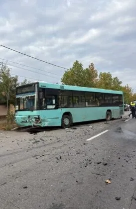 Un autobuz de culoare turcoaz stă pe o stradă cu resturi împrăștiate pe asfalt în fața sa, sub un cer înnorat.