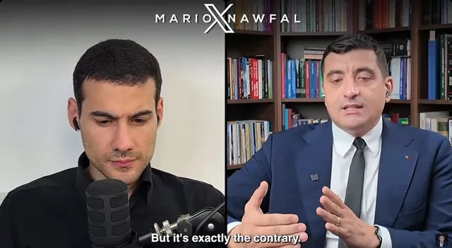 Un bărbat cu cămașă neagră privește în jos lângă un microfon, în timp ce un alt bărbat în costum și cravată vorbește în fața unei biblioteci.