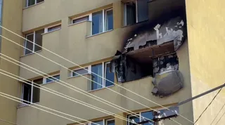 O clădire cu mai multe etaje prezintă urme de ardere și zone de fațadă distruse lângă ferestrele de la etajele superioare.