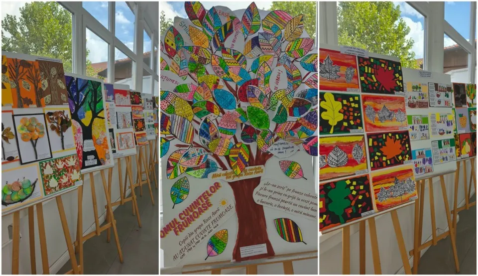 Diverse picturi colorate cu teme de toamnă sunt expuse pe suporturi de lemn într-o încăpere luminoasă cu ferestre mari.