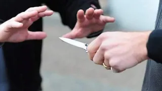O mână ține un cuțit deschis, în timp ce o altă persoană întinde mâinile spre ea.