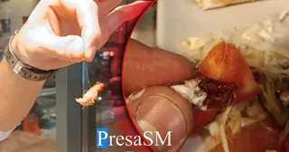 O mână ține un fir subțire cu un fragment de obiect la capăt, suprapus peste o farfurie cu salată și roșii.