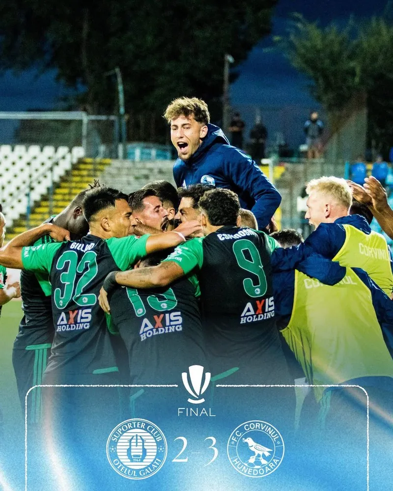 Un grup de fotbaliști în echipamente sportive verzi și negre se îmbrățișează pe un teren de fotbal sub luminile stadionului.