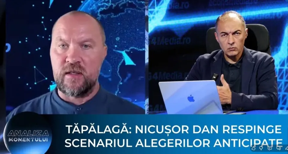 Un bărbat cu barbă și unul cu părul scurt stau în fața unor ecrane albastre, având un laptop deschis în prim-plan.