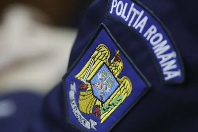 Un emblem brodat pe o uniformă albastră prezintă un acvilă aurie cu o sabie și un sceptru pe un fundal albastru.
