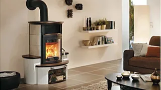 O sobă modernă cu lemne arde pe un foc viu într-un living amenajat, cu rafturi de perete, canapea și masă de cafea.