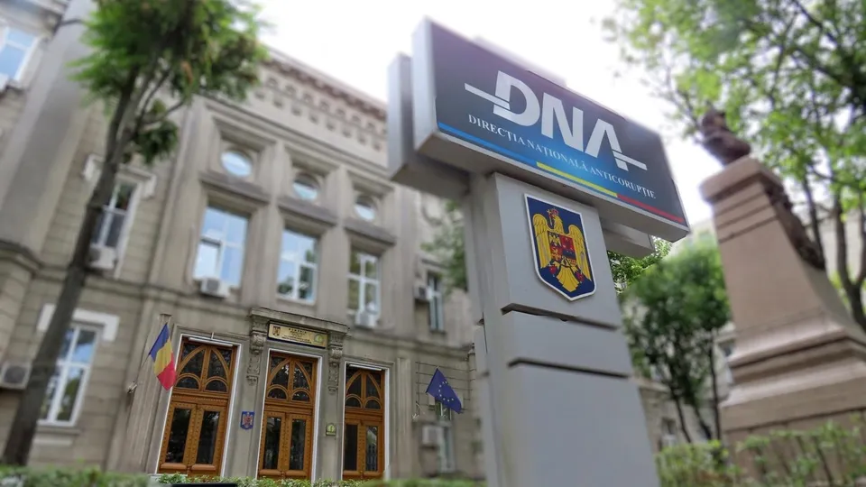 Un semn cu inscripția DNA este poziționat în prim-plan în fața unei clădiri cu ferestre mari și uși din lemn.