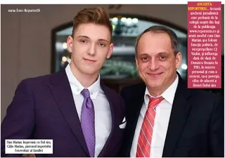 Un bărbat cu cravată roșu și un tânăr cu cravată mov stau unul lângă altul în costume în fața unui fundal neclar.
