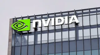 Un semn cu textul NVIDIA și un logo verde sunt montate pe fațada unei clădiri cu ferestre mari de sticlă.