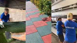 Trei bărbați lucrează la producția de dale colorate din cauciuc, fiind vizibile două persoane în timp ce una manipulează o suprafață verde.