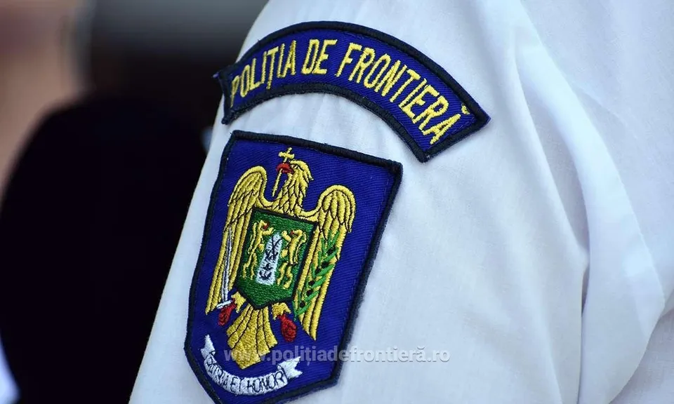 Un emblema brodată cu un acvile și textul POLIȚIA DE FRONTIERĂ este atașată pe o uniformă albă.