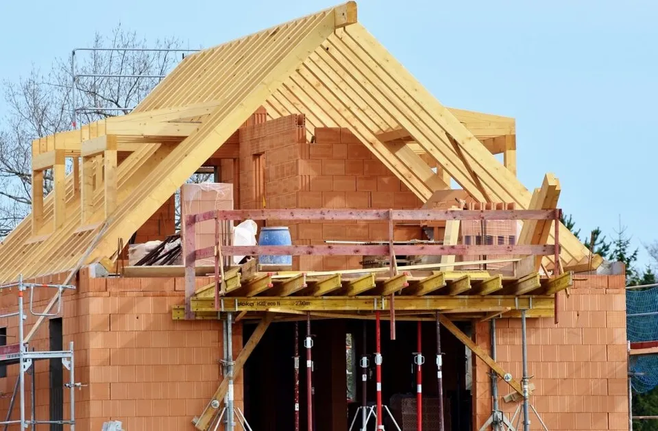 O structură de construcție din cărămizi și grinzi de lemn este susținută de niște stâlpi metalici sub un acoperiș în lucru.