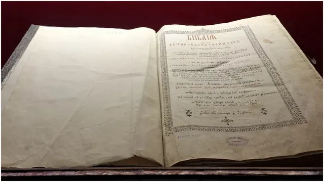 O carte veche deschisă prezintă pagini de hârtie îngălbenită cu text scris și margini decorate cu modele geometrice și florale.