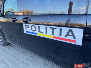 Un autovehicul negru prezintă inscripția POLITIA pe o suprafață albă sub care se află o dungă colorată.