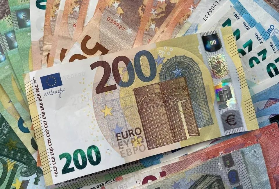 Mai multe bancnote de euro de diferite valori sunt întinse pe o suprafață plană.