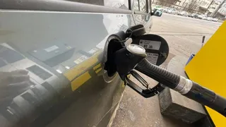 Un furtun de pompare a carburantului este introdus în orificiul de umplere al unui vehicul gri.