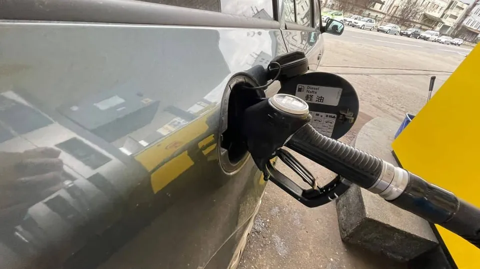 Un furtun de pompare a carburantului este introdus în orificiul de umplere al unui vehicul gri.
