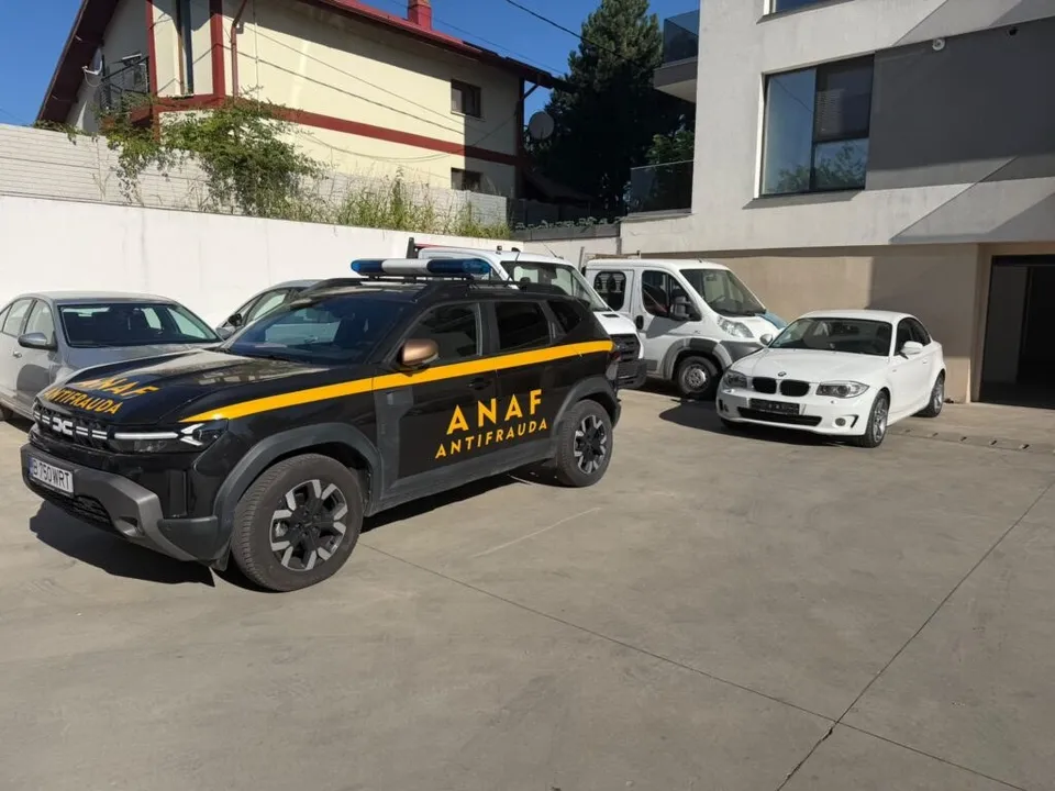 Un SUV negru cu inscripții galbene ANAF ANTIFRAUDA este parcat pe o suprafață de beton lângă alte vehicule albe.