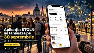 O mână ține un smartphone care afișează o aplicație mobilă, în timp ce în fundal se află oameni și clădiri într-un decor urban la apus.