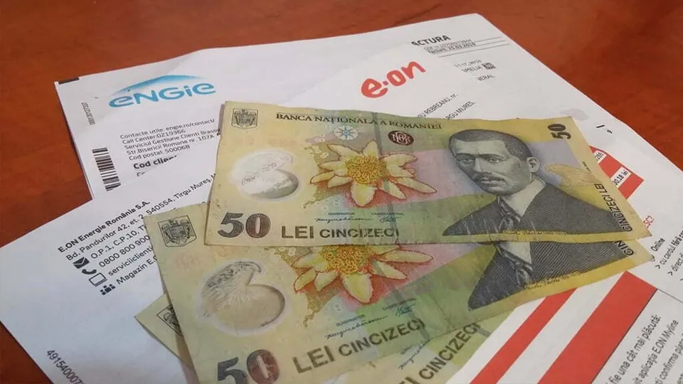 Două bancnote de cincizeci de lei sunt așezate peste facturi de la furnizorii Engie și e.on pe o suprafață maro.