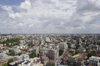 O vedere panoramică asupra unui oraș cu numeroase clădiri de diverse înălțimi sub un cer cu nori albi și cenușii.