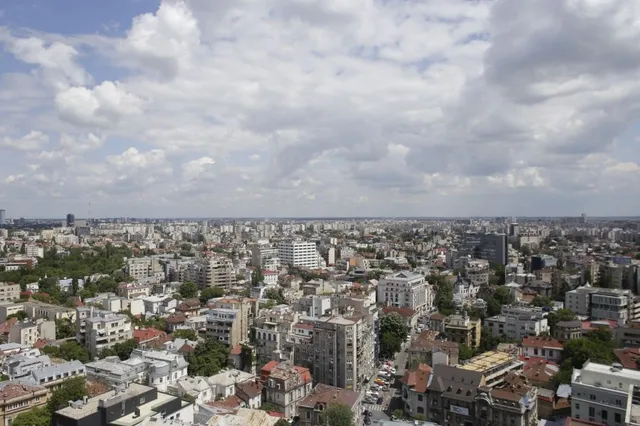 O vedere panoramică asupra unui oraș cu numeroase clădiri de diverse înălțimi sub un cer cu nori albi și cenușii.
