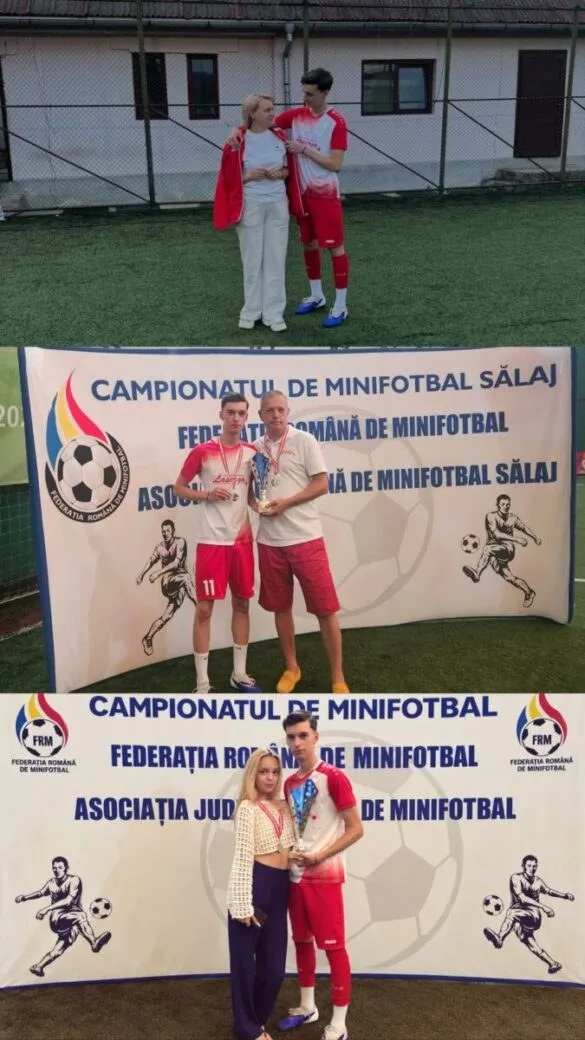 Un bărbat și un tânăr jucător în echipament roșu poartă un trofeu în fața unui banner alb cu grafică de fotbal.