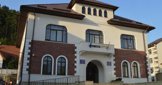 O clădire cu fațadă din cărămidă și zone albe, având ferestre arcuite la parter și ferestre dreptunghiulare la etaj sub un acoperiș înclinat maroniu.