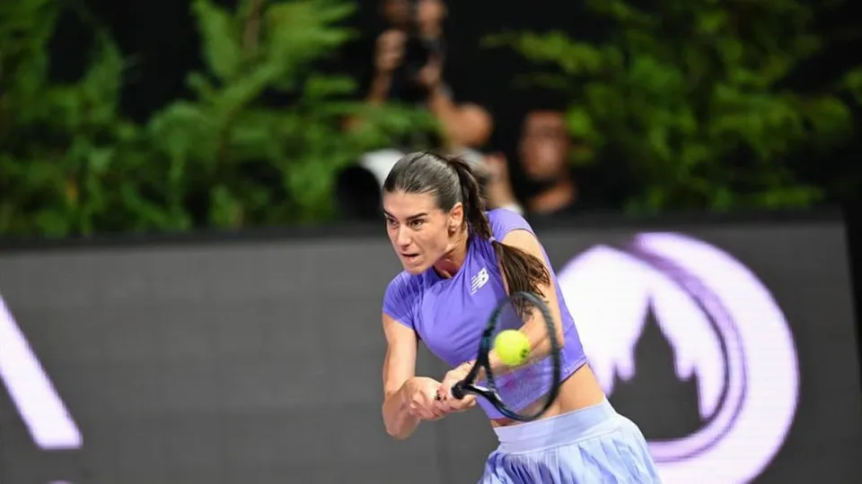 O femeie cu părul legat într-o coadă de cal lovește o minge de tenis cu o rachetă pe un teren de joc.