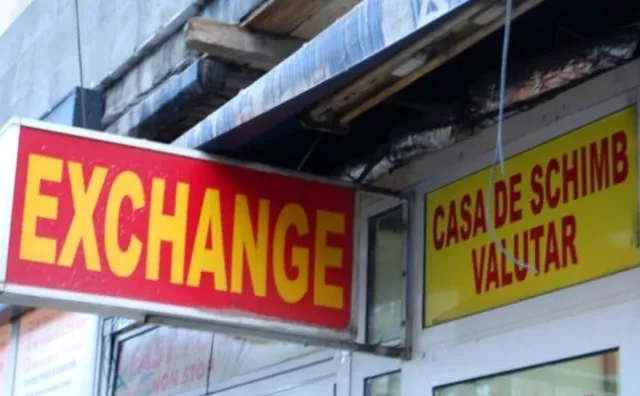 Două semne de indicare, unul roșu cu text galben și unul galben cu text roșu, sunt montate pe fațada unei clădiri.