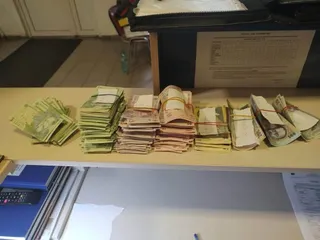 Mai multe teancuri de bancnote de diferite culori sunt așezate pe o suprafață plană lângă un calculator și un aparat de calcul.