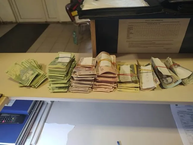 Mai multe teancuri de bancnote de diferite culori sunt așezate pe o suprafață plană lângă un calculator și un aparat de calcul.