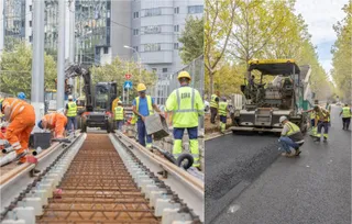 Oameni în echipamente de protecție portocalii și galben reflectante lucrează pe un șantier lângă șine de tramvai și utilaje de pavaj.