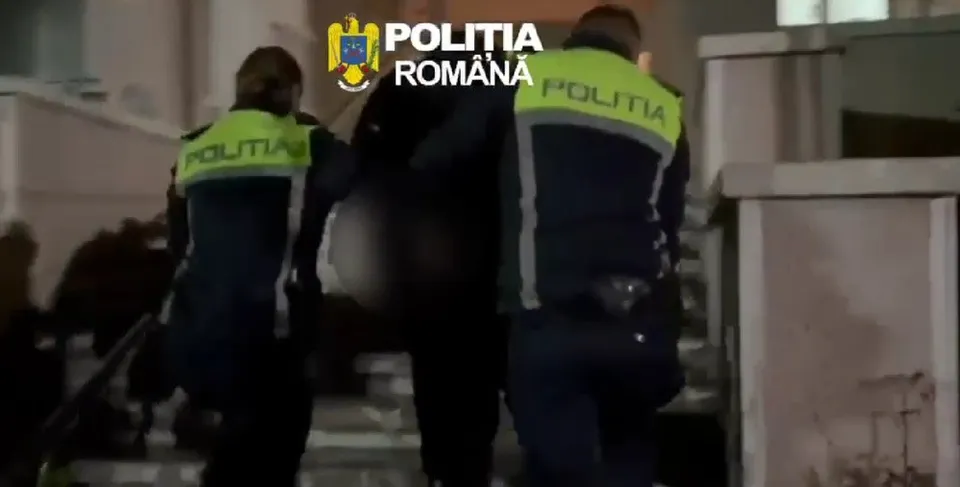 Trei persoane purtând uniformă în culori închise cu benzi reflectorizante verzi sunt poziționate în spatele unei alte persoane în noapte.