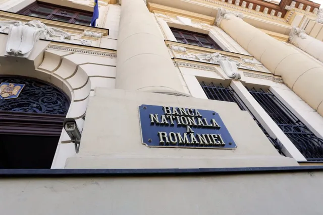 O placă albastră cu textul Banca Națională a României este montată pe fațada unei clădiri cu coloane și ferestre gri.