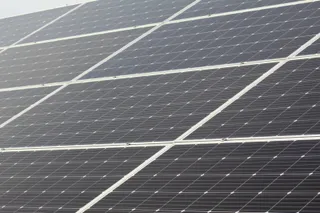 Mai multe panouri solare de culoare închisă sunt dispuse în rânduri paralele sub un unghi înclinat.