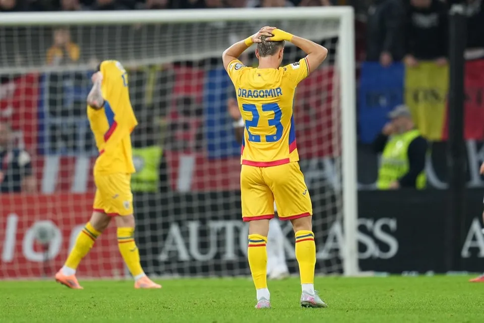 Doi fotbaliști în echipament galben stau pe terenul de fotbal cu mâinile pe cap sau pe față, în fața unei porți de fotbal.